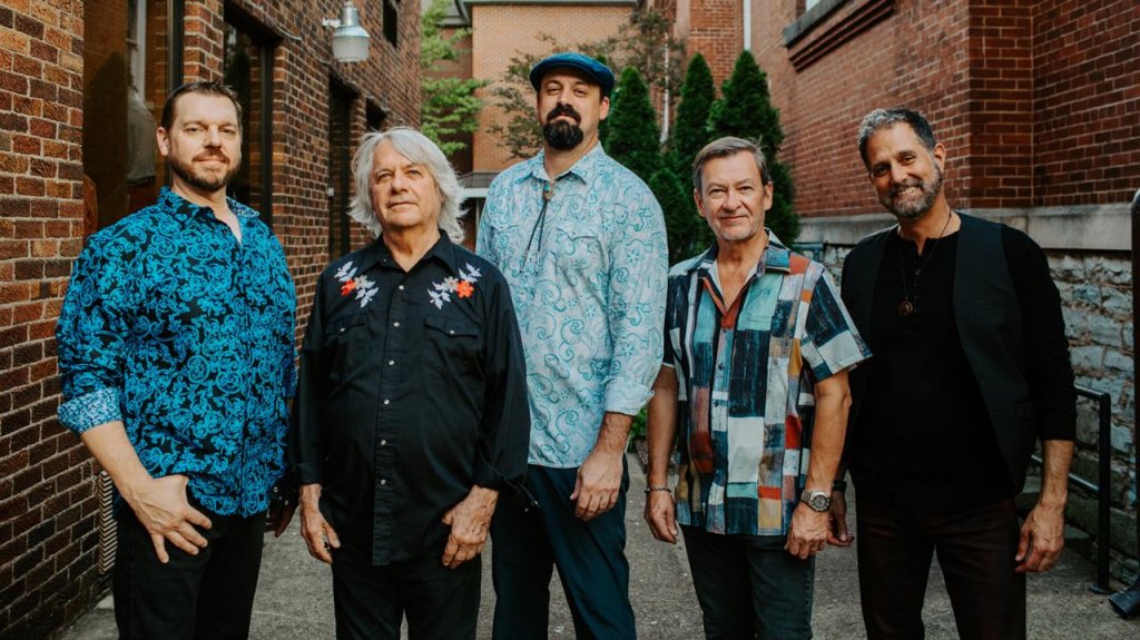 Pure Prairie League Five men stand together outdoors, smiling, wearing colorful shirts and casual attire in Williamson County, Tennessee.