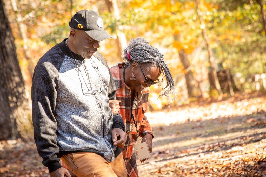 Deer Run's Fall Marriage Retreat A man and woman walk together in a forest, smiling and enjoying the autumn leaves in Williamson County, Tennessee.