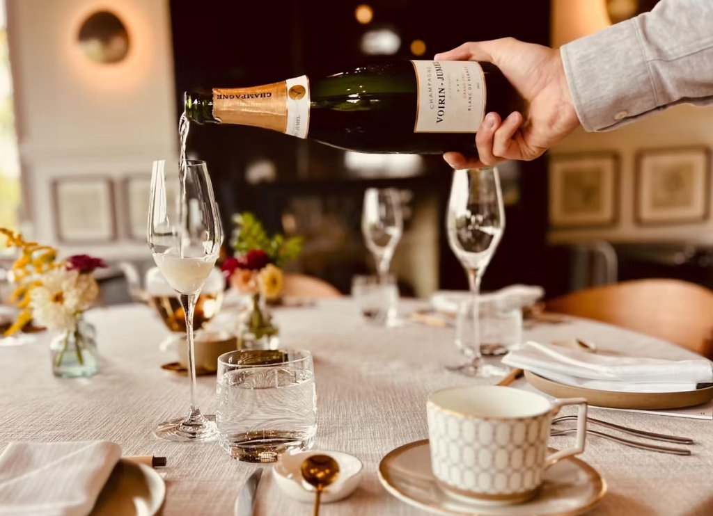 Tea by Southall A hand pours champagne into a glass at an elegantly set dining table in Williamson County, Tennessee.