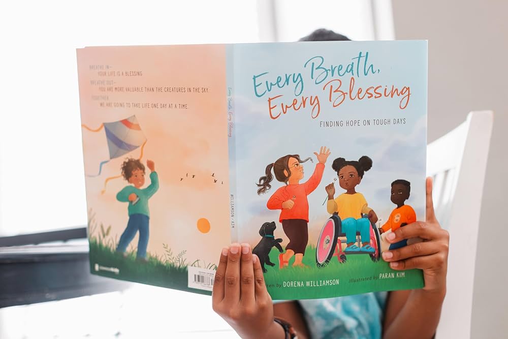 Dorena Williamson Children's Book Signing A child holds a colorful book titled 'Every Breath, Every Blessing' featuring diverse children playing outdoors in Williamson County, Tennessee.