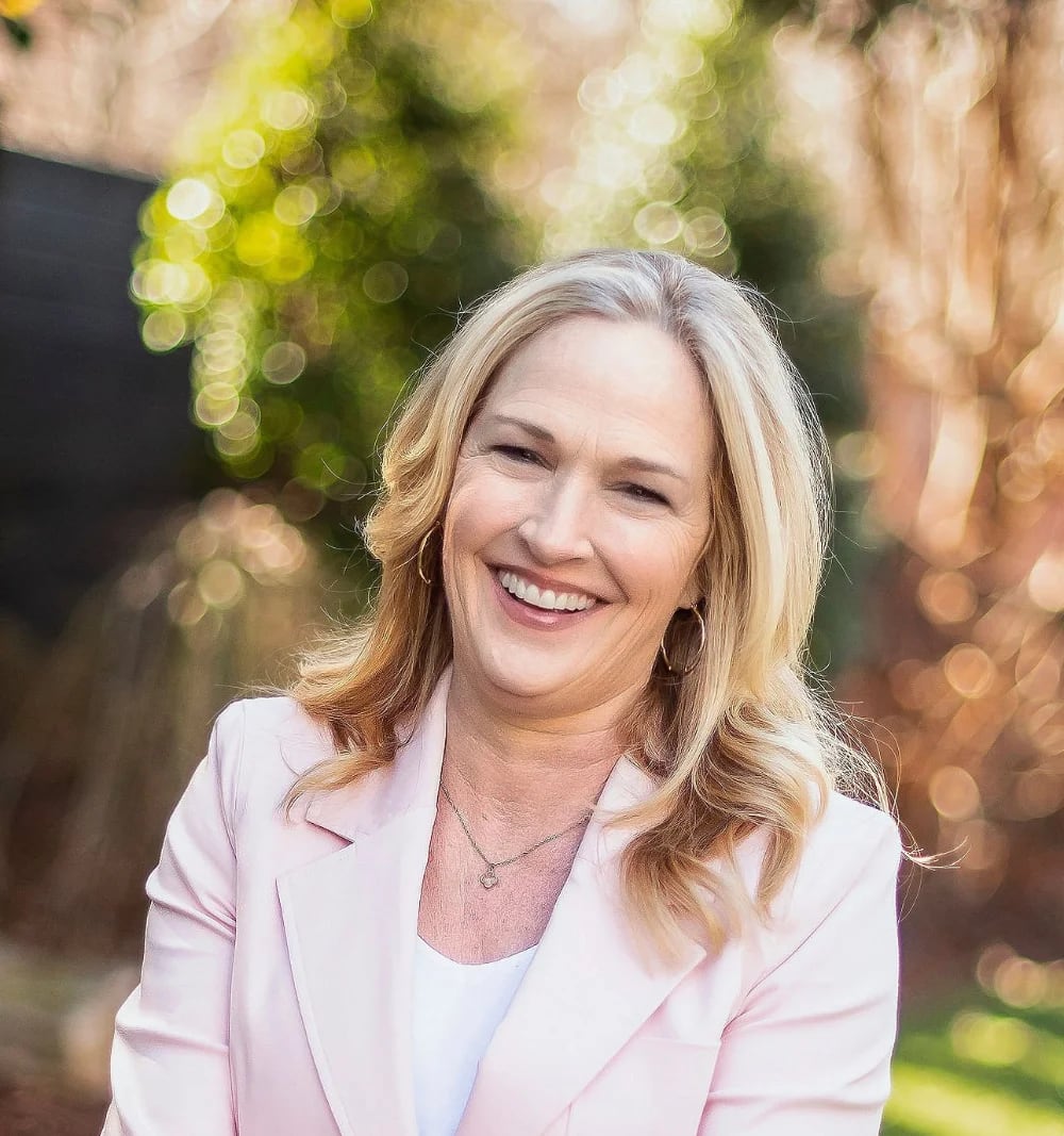Tricia Thornton | Author Event A smiling woman with blonde hair wearing a pink blazer outdoors in Williamson County, Tennessee.