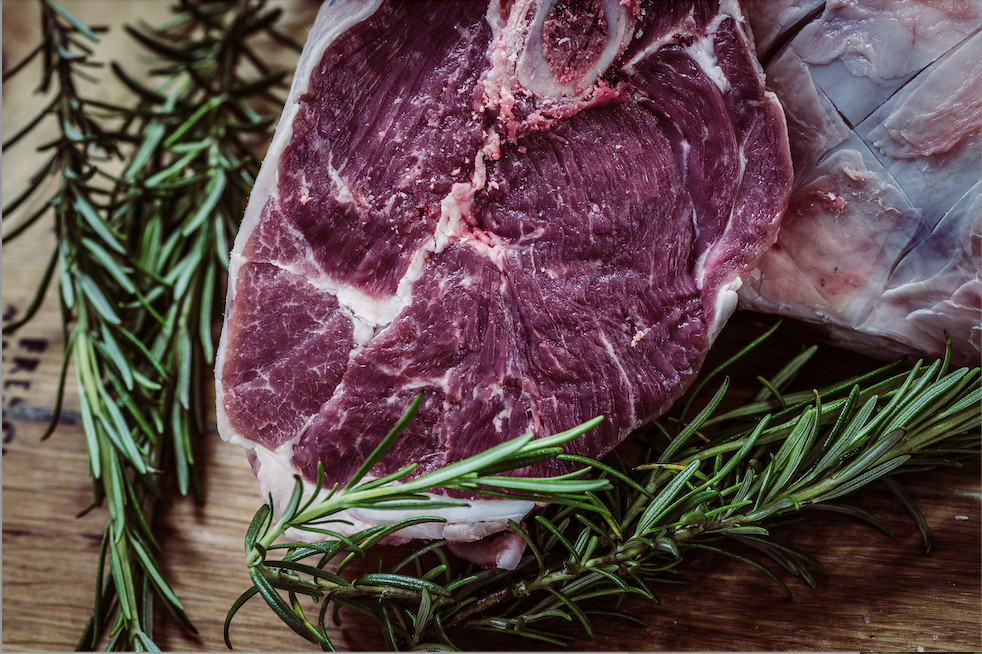 A close-up of a raw steak with visible marbling, accompanied by fresh rosemary sprigs in Williamson County, Tennessee.