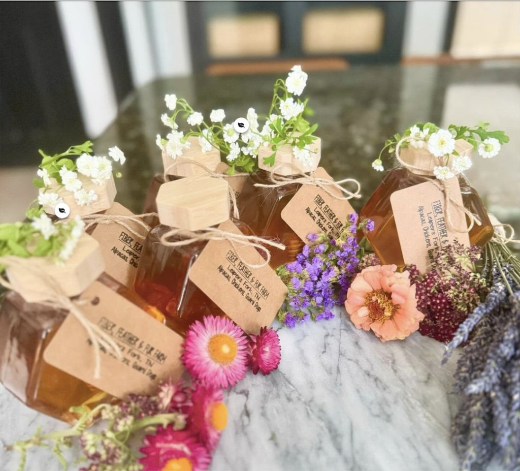 Six hexagonal honey jars with wooden lids, tied with twine and adorned with flowers in Williamson County, Tennessee.