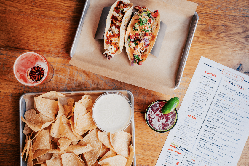 Taco ’Bout Tasty: 10 of Our Favorite Franklin Taco Joints A tray of two tacos with various toppings, a bowl of white sauce, tortilla chips, and two colorful drinks in Williamson County, Tennessee.