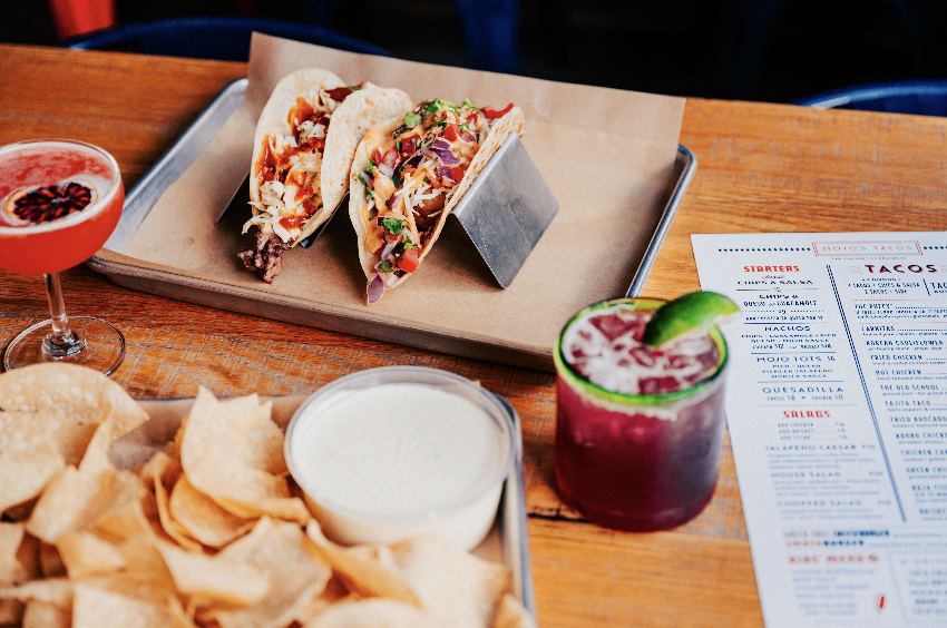 Taco ’Bout Tasty: 10 of Our Favorite Franklin Taco Joints A tray of tacos, chips, salsa, and two colorful cocktails on a wooden table in Williamson County, Tennessee.