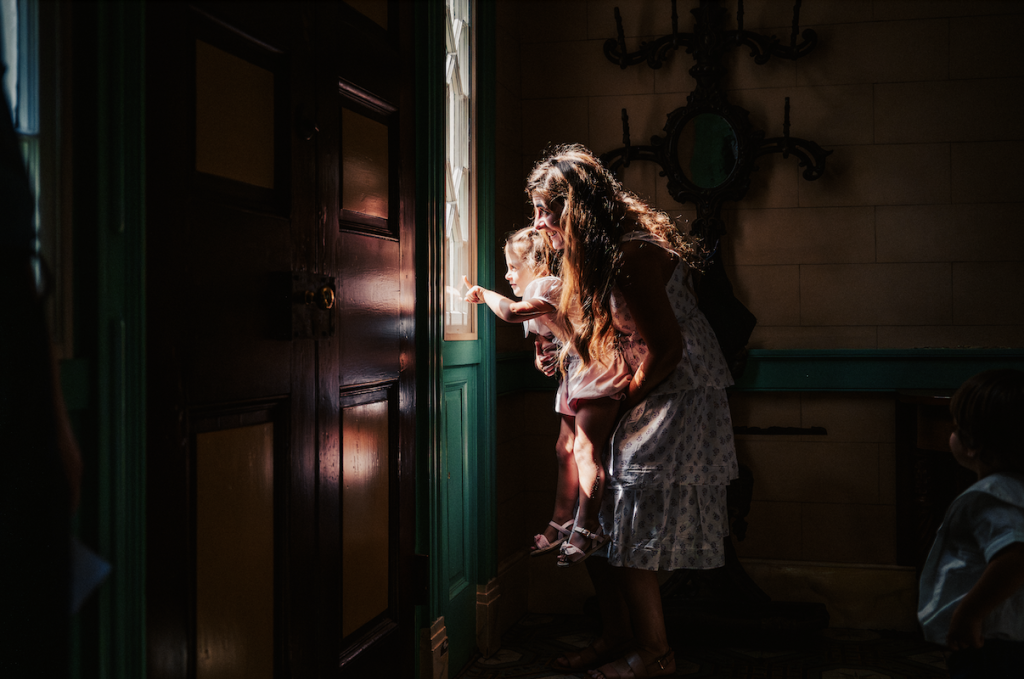 A woman holds a child as they both reach out to touch a sunlit door in Williamson County, Tennessee.