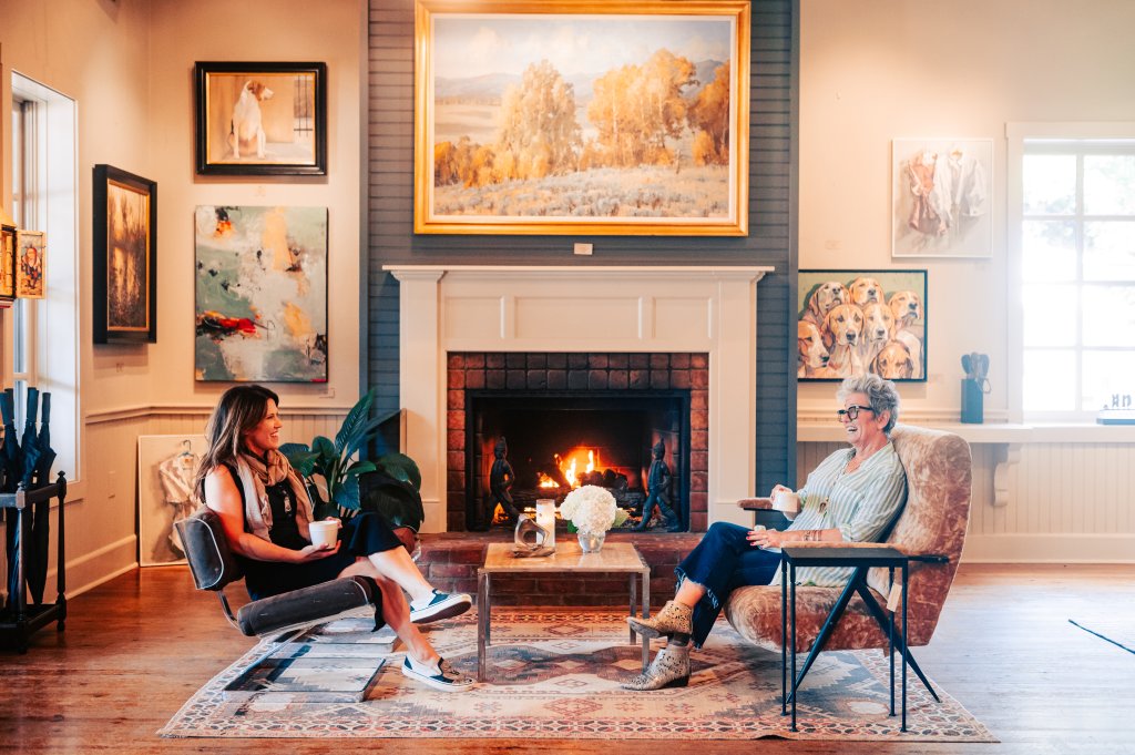 Two women enjoy tea by a cozy fireplace in a warmly decorated living room in Williamson County, Tennessee.
