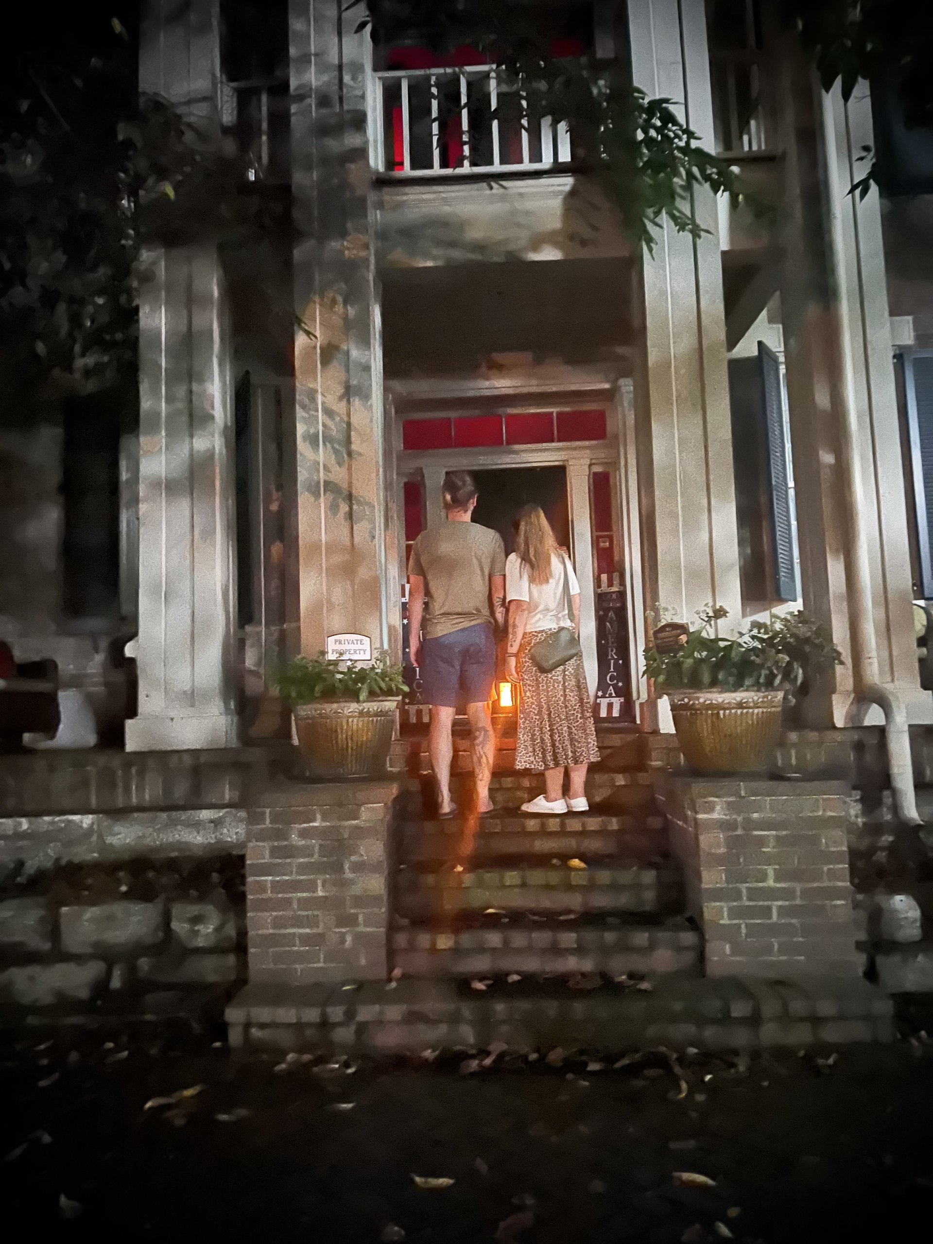 A couple walks up the steps of a dimly lit, historic-looking house at night in Williamson County, Tennessee.