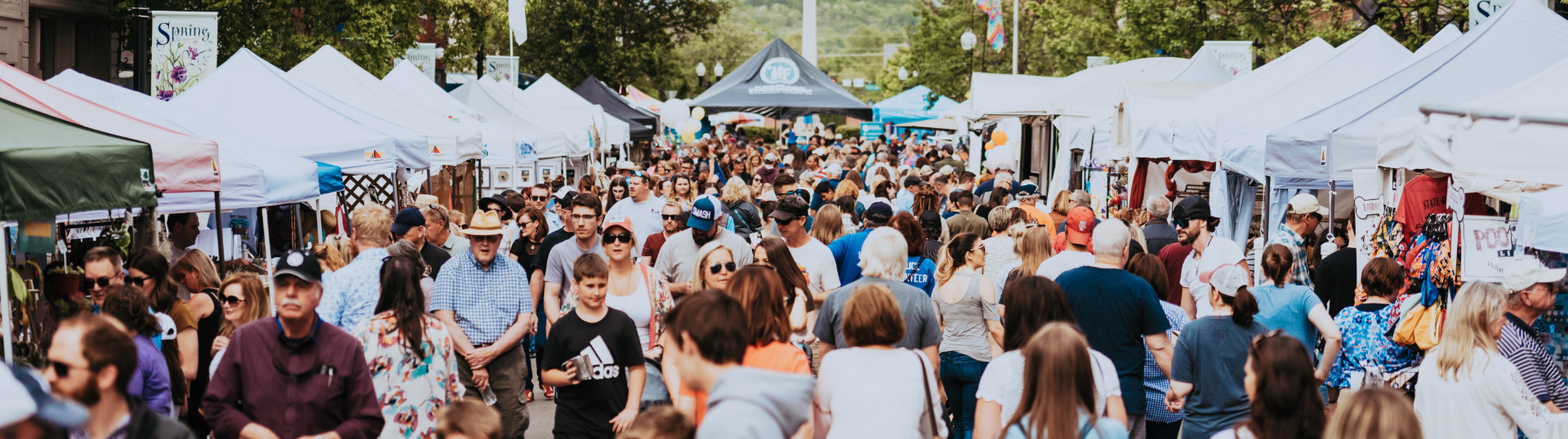 A bustling outdoor market with numerous white tents and a large crowd of shoppers in Williamson County, Tennessee.