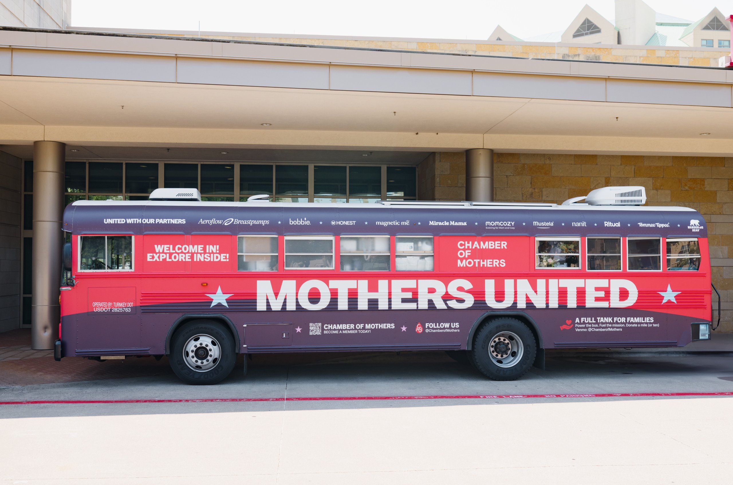 A red bus with 'Mothers United' and 'Chamber of Mothers' written on it is parked outside a building in Williamson County, Tennessee.