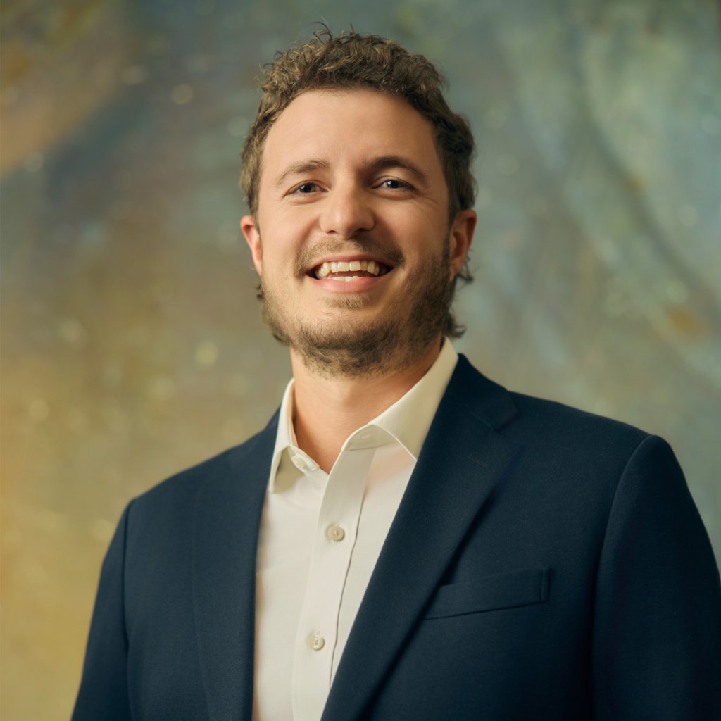 Brock Hurtle A smiling man with curly hair wearing a dark suit and white shirt in Williamson County, Tennessee.