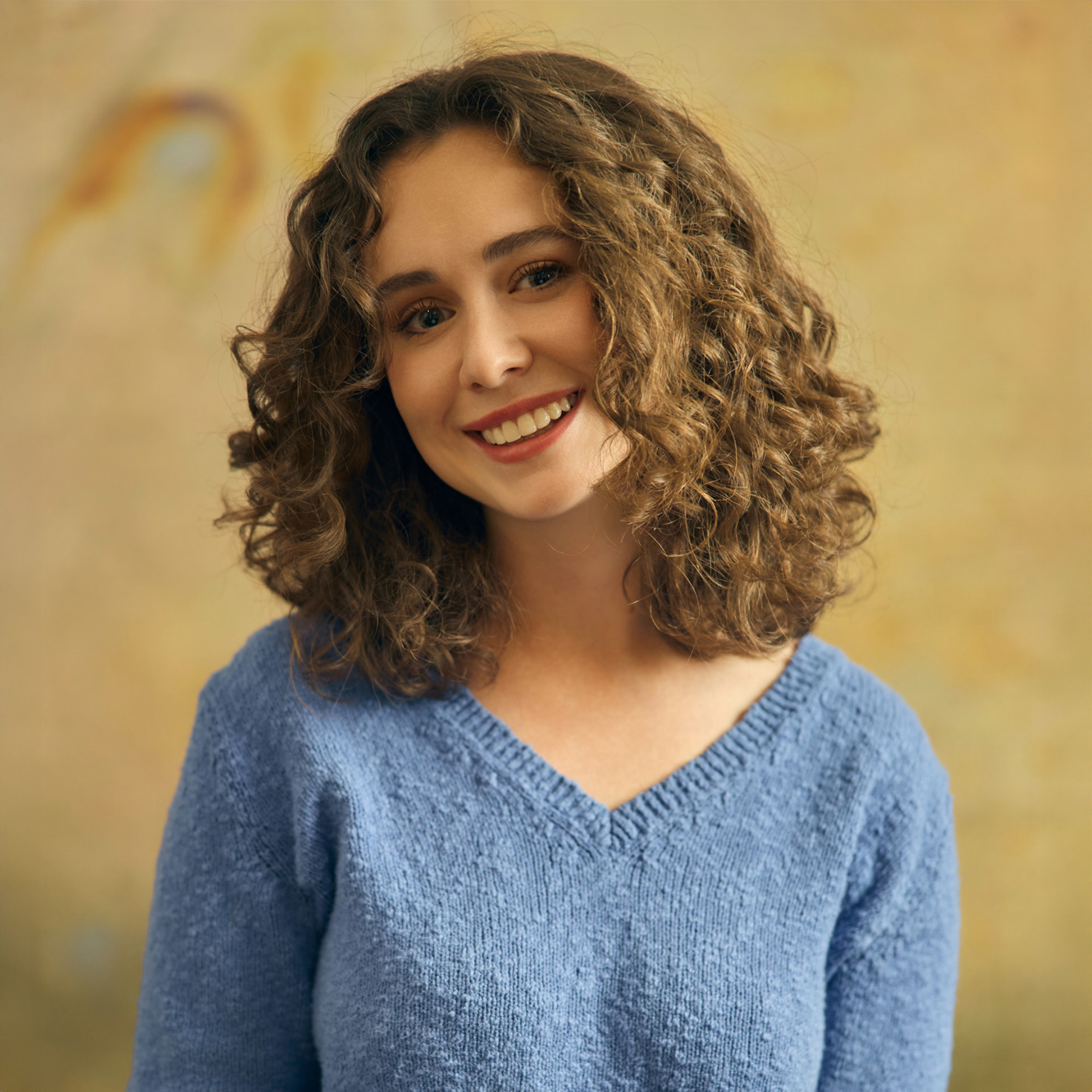 Meet The Team A woman with curly hair smiles brightly, wearing a blue sweater in Williamson County, Tennessee.