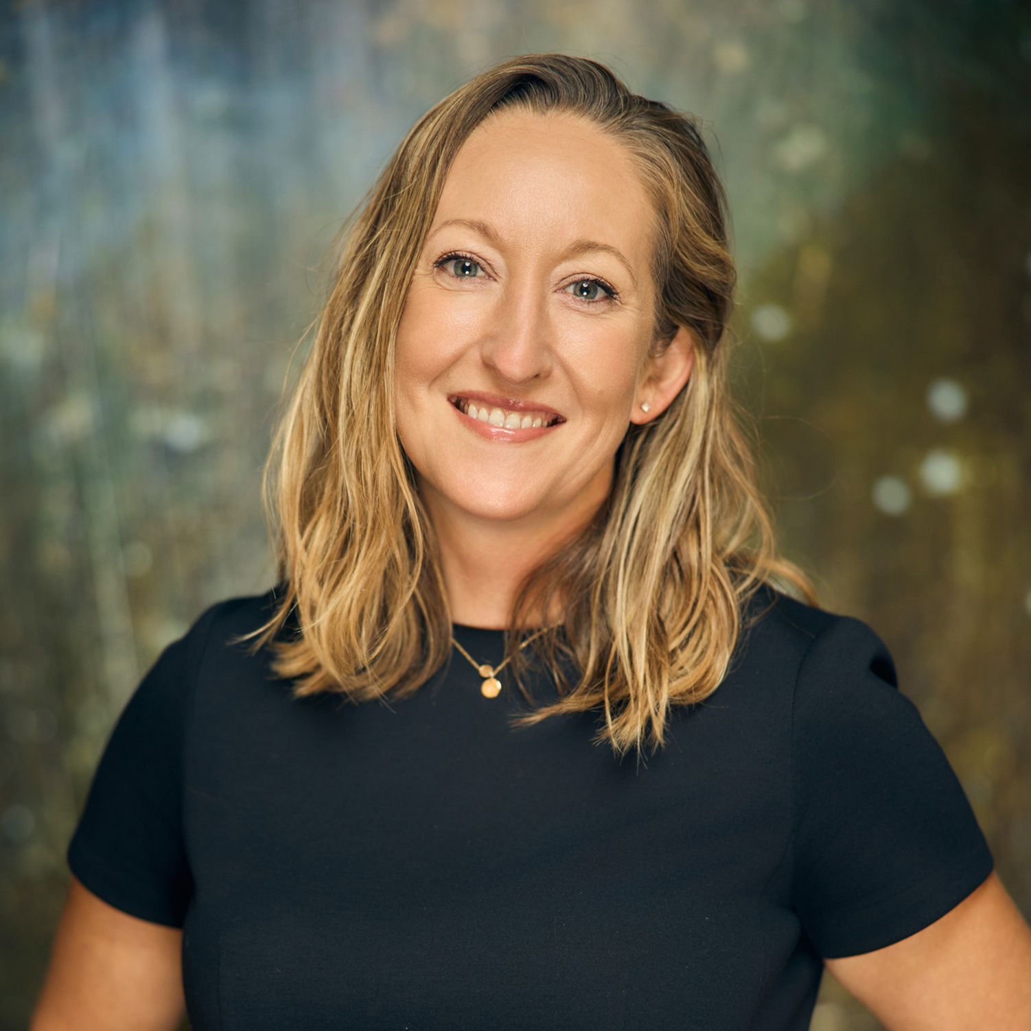 Meet The Team A smiling woman with blonde hair wearing a black shirt and a gold necklace in Williamson County, Tennessee.