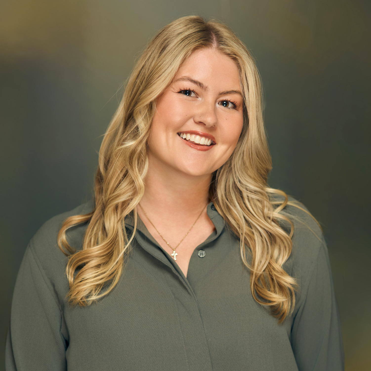 Meet The Team A smiling woman with long blonde hair wearing a green shirt and a cross necklace in Williamson County, Tennessee.