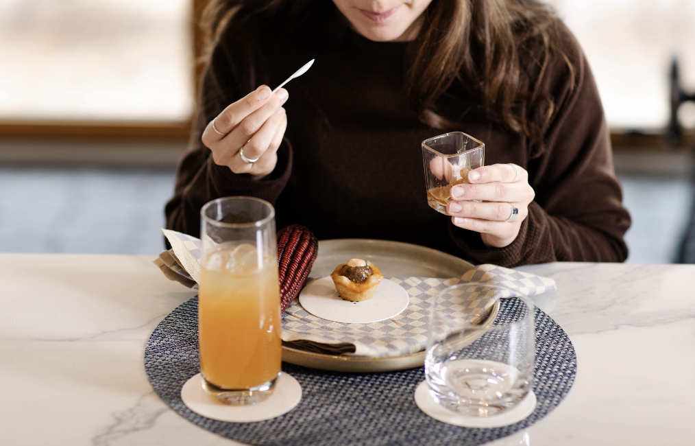 A woman enjoys a small pastry with a spoon and sips from a glass of orange juice in Williamson County, Tennessee.