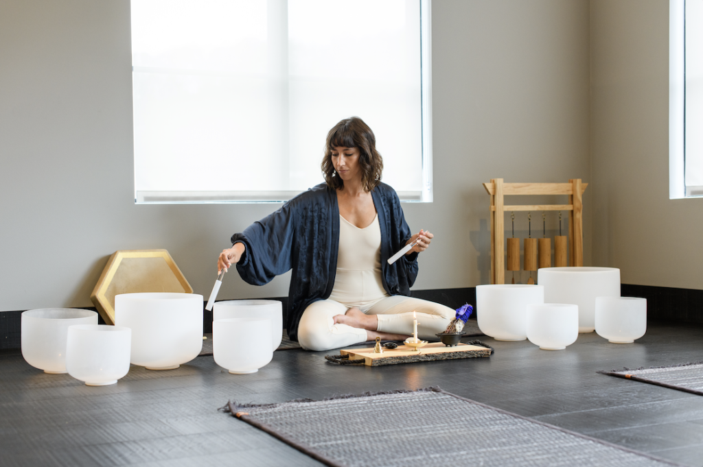Woman meditating with singing bowls in a serene, minimalist room in Williamson County, Tennessee.