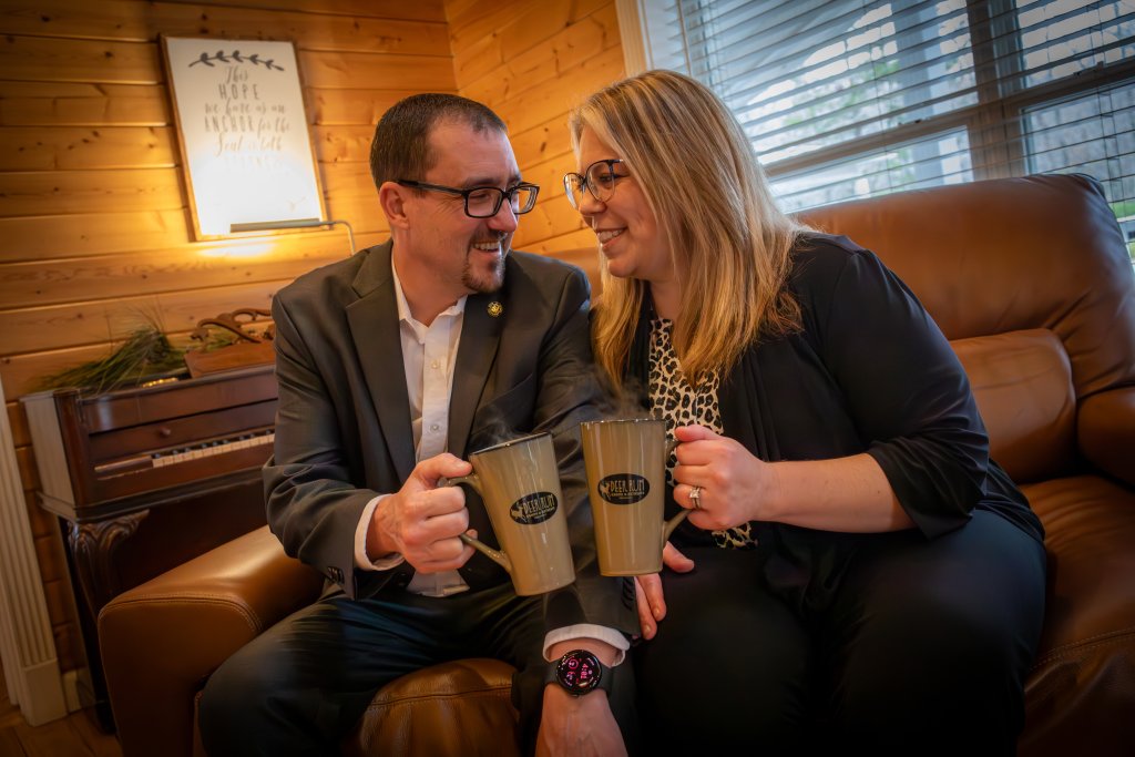 A man and woman in business attire share a moment over coffee in a cozy, rustic living room in Williamson County, Tennessee.