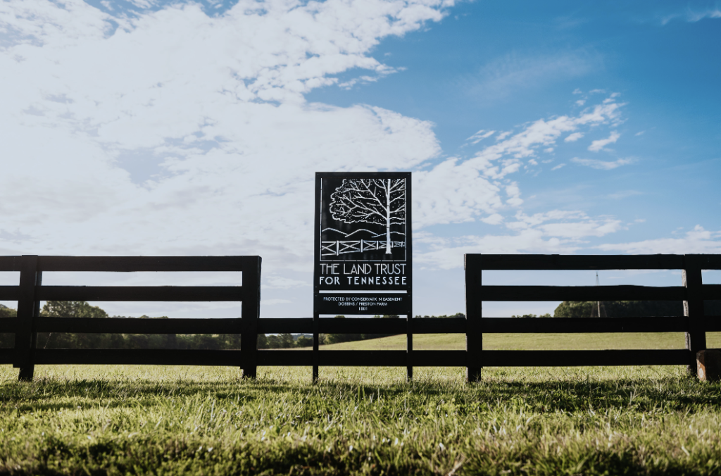 Leiper's Fork, Tennessee: The Revival of a Small-Town Gem A black fence with a sign for The Land Trust for Tennessee in a grassy field in Williamson County, Tennessee.