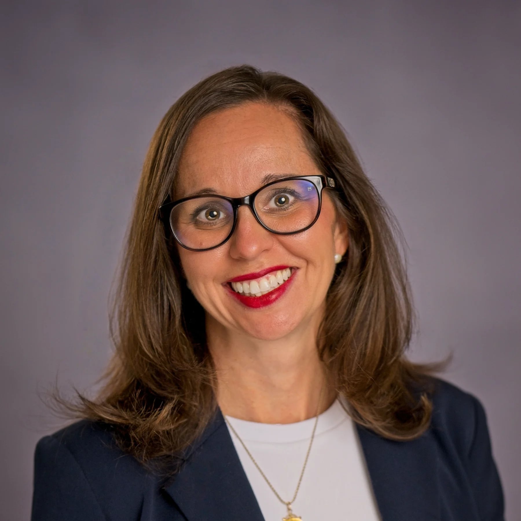 A smiling woman with glasses and red lipstick wearing a navy blazer and white shirt in Williamson County, Tennessee.