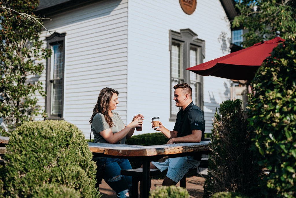 Cafes & Bars A couple enjoys coffee at an outdoor table under a red umbrella, surrounded by greenery in Williamson County, Tennessee.