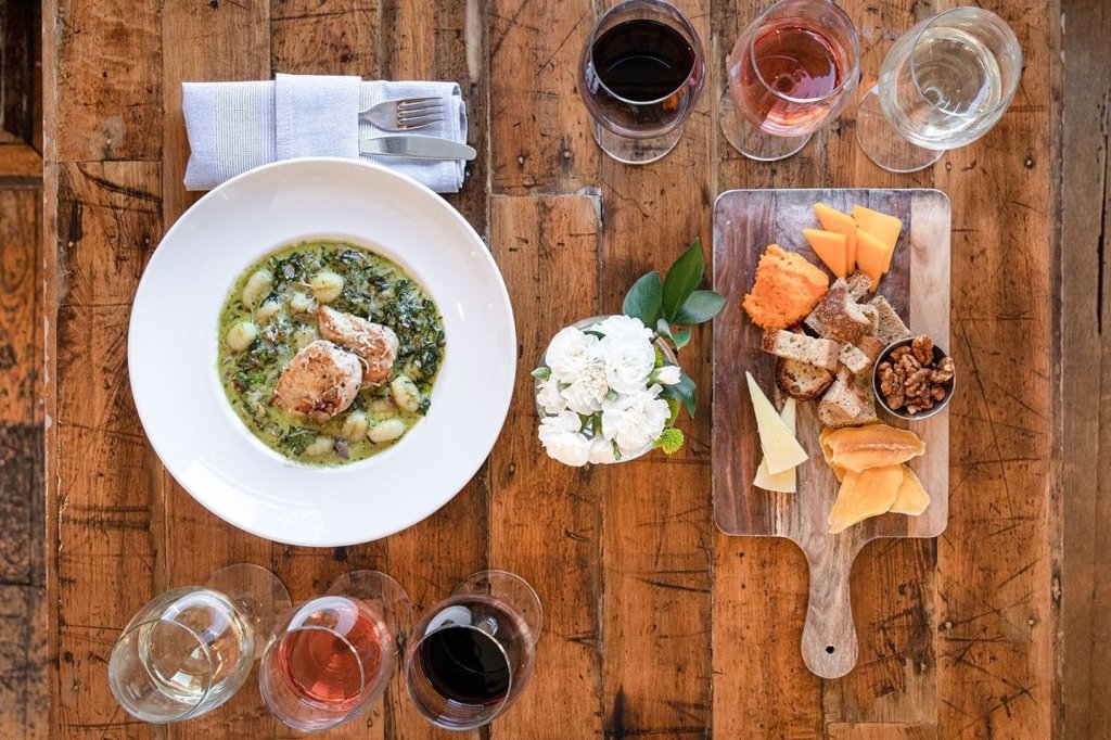 Cafes & Bars A rustic wooden table set with a gourmet meal, wine glasses, and a cheese board in Williamson County, Tennessee.