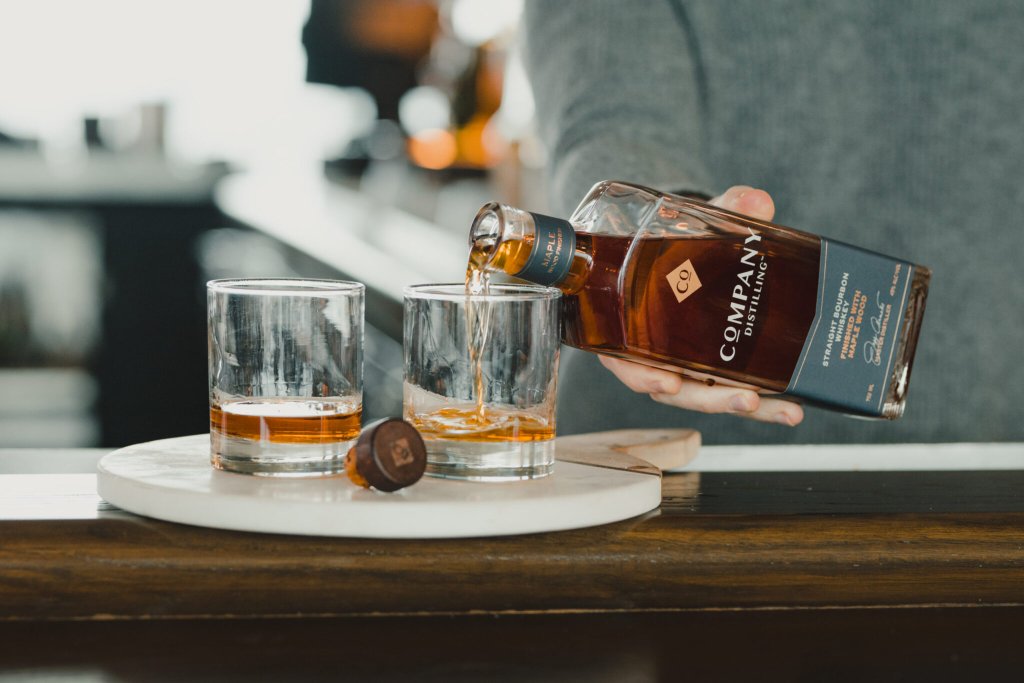 Cafes & Bars A person pours whiskey from a bottle into two glasses on a marble coaster in Williamson County, Tennessee.