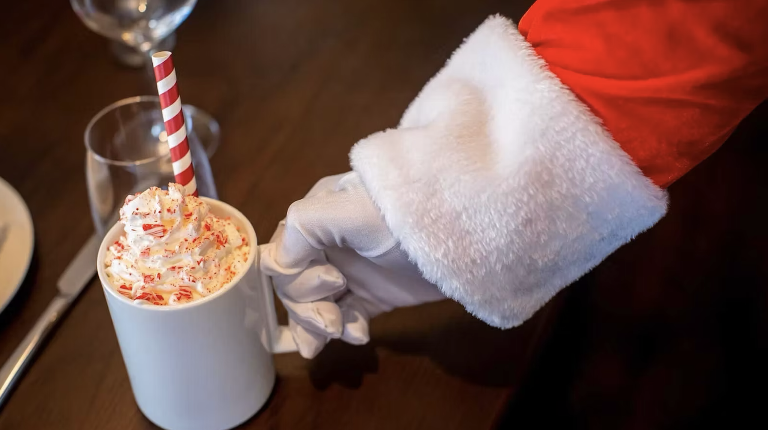 Santa Claus offers a mug of peppermint hot chocolate with whipped cream and a candy cane straw in Williamson County, Tennessee.