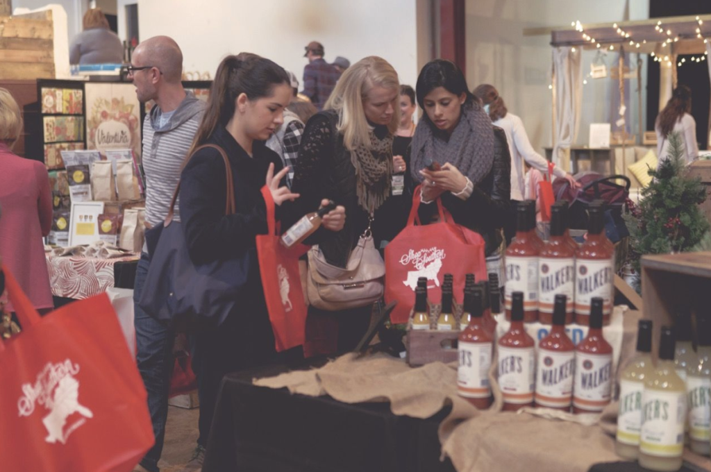 Women examine bottles of Walker's beverages at a bustling market stand in Williamson County, Tennessee.