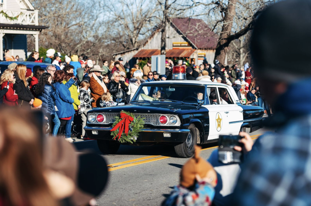 Celebrating Christmas in Franklin, Tennessee: A Guide to Local Holiday Traditions A vintage police car adorned with a wreath leads a festive parade down a tree-lined street in Williamson County, Tennessee.