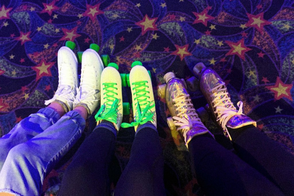 Three pairs of roller skates with neon green laces on a starry, colorful carpet in Williamson County, Tennessee.