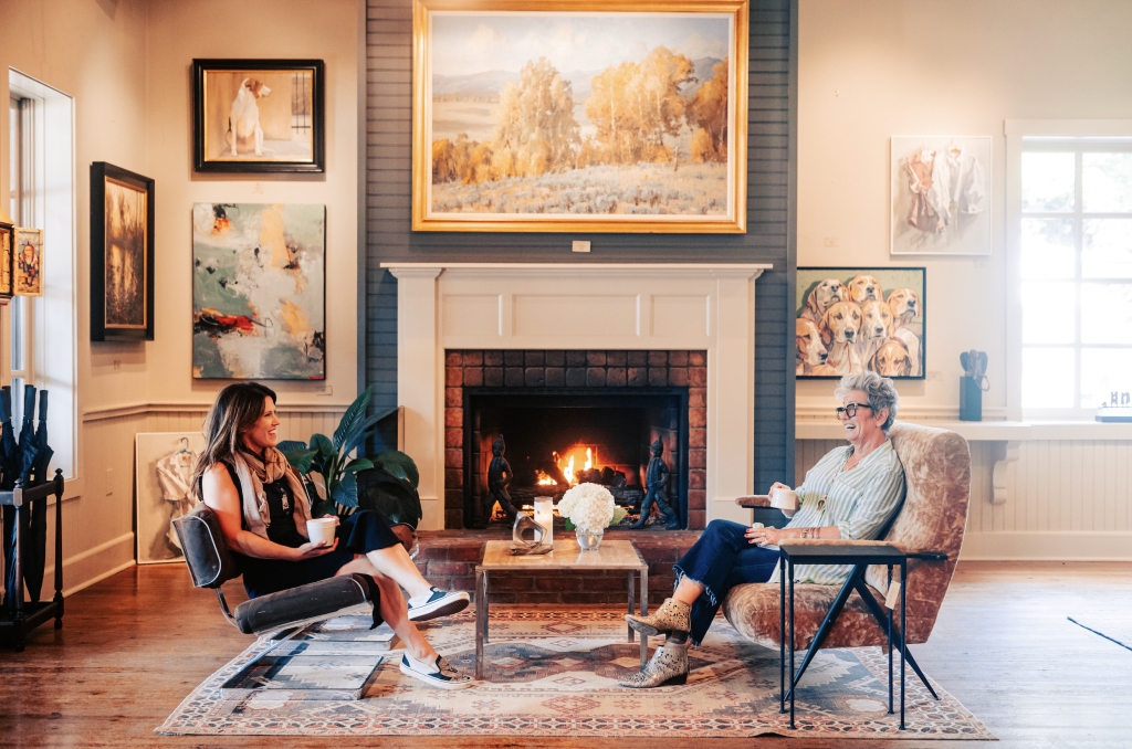 Two women enjoy coffee by a fireplace in a cozy, art-filled living room in Williamson County, Tennessee.