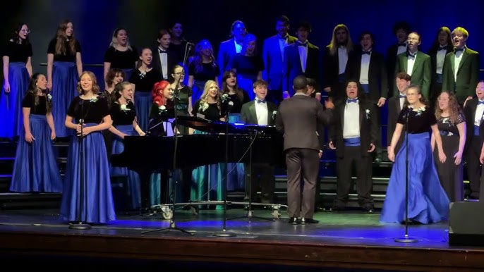 A large choir performs on stage, dressed in formal attire with blue accents in Williamson County, Tennessee.