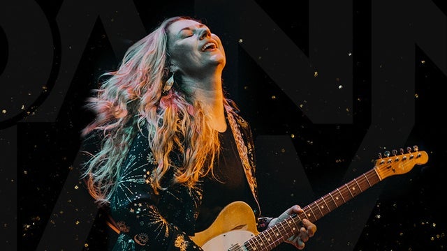 A woman with long, flowing hair passionately plays an electric guitar on stage, her eyes closed in musical ecstasy in Williamson County, Tennessee.