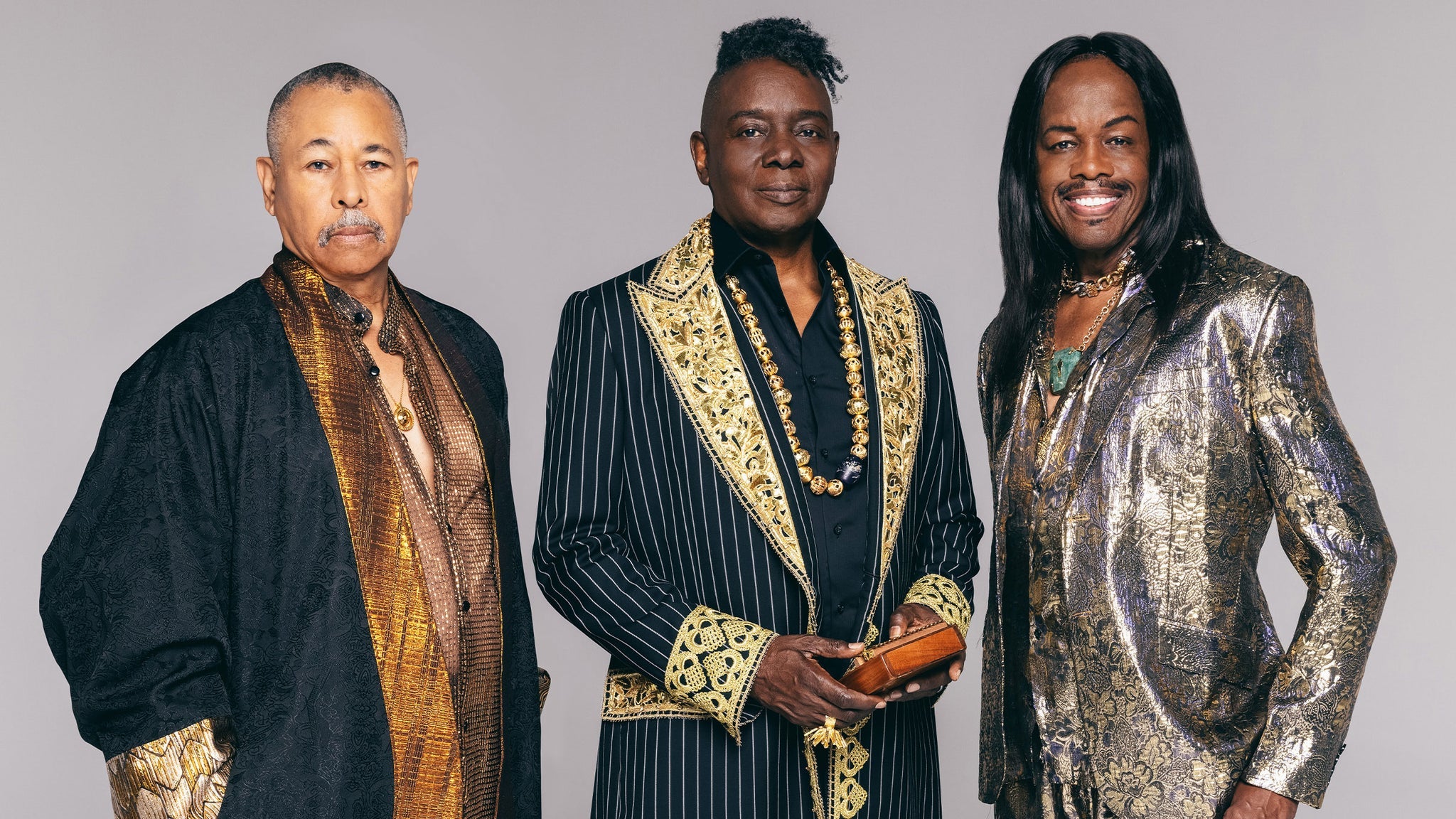 Three men dressed in elaborate, ornate outfits with gold and jewel embellishments stand together against a plain background in Williamson County, Tennessee.