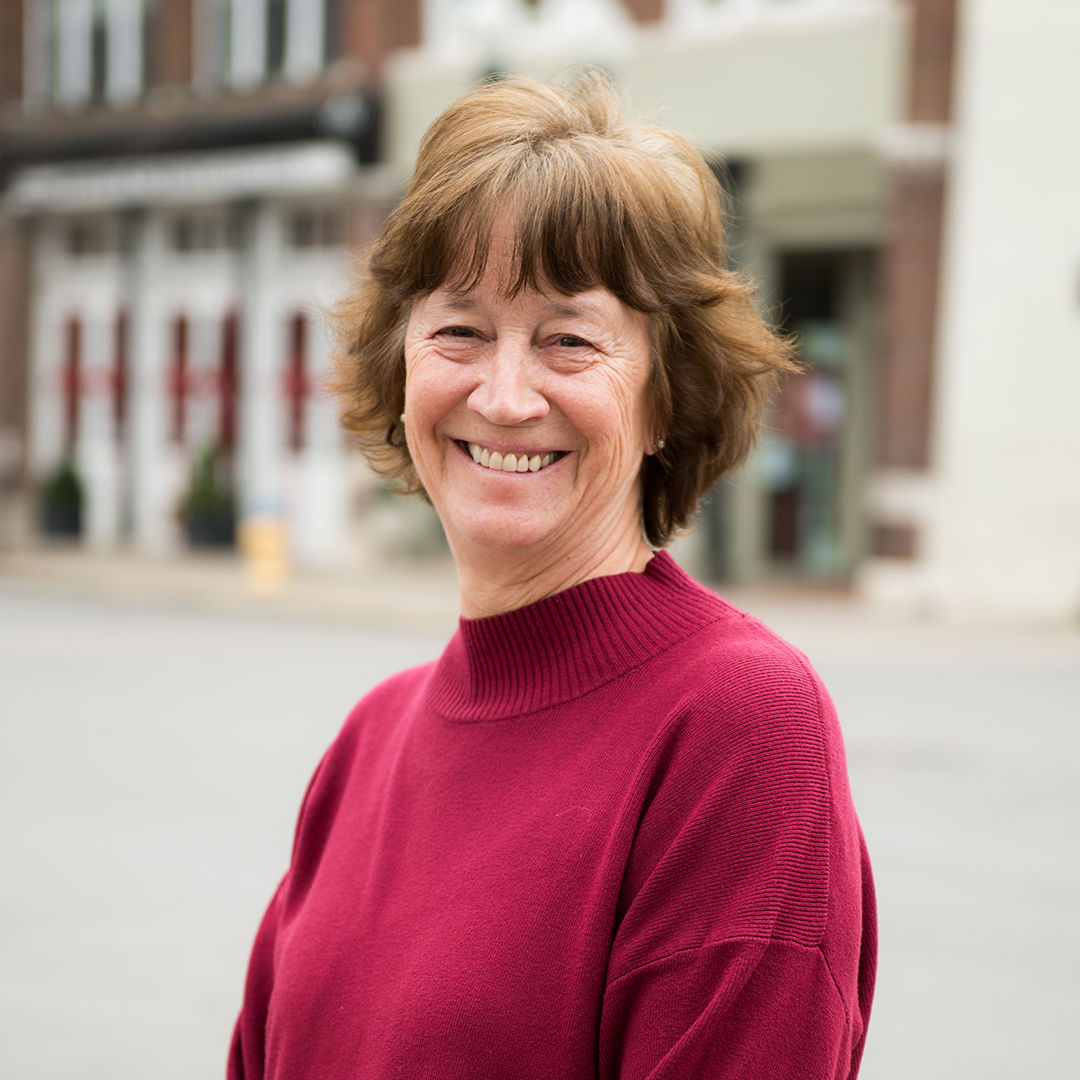 A woman with short brown hair is smiling broadly, wearing a maroon turtleneck sweater in Williamson County, Tennessee.