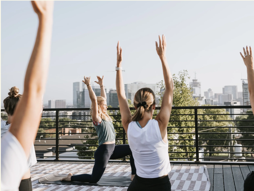 A group of women practicing yoga on a rooftop with a city skyline in the background in Williamson County, Tennessee.