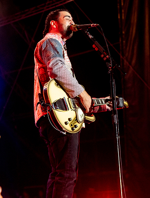 A musician passionately performs on stage, strumming a vibrant yellow electric guitar while singing into a microphone in Williamson County, Tennessee.