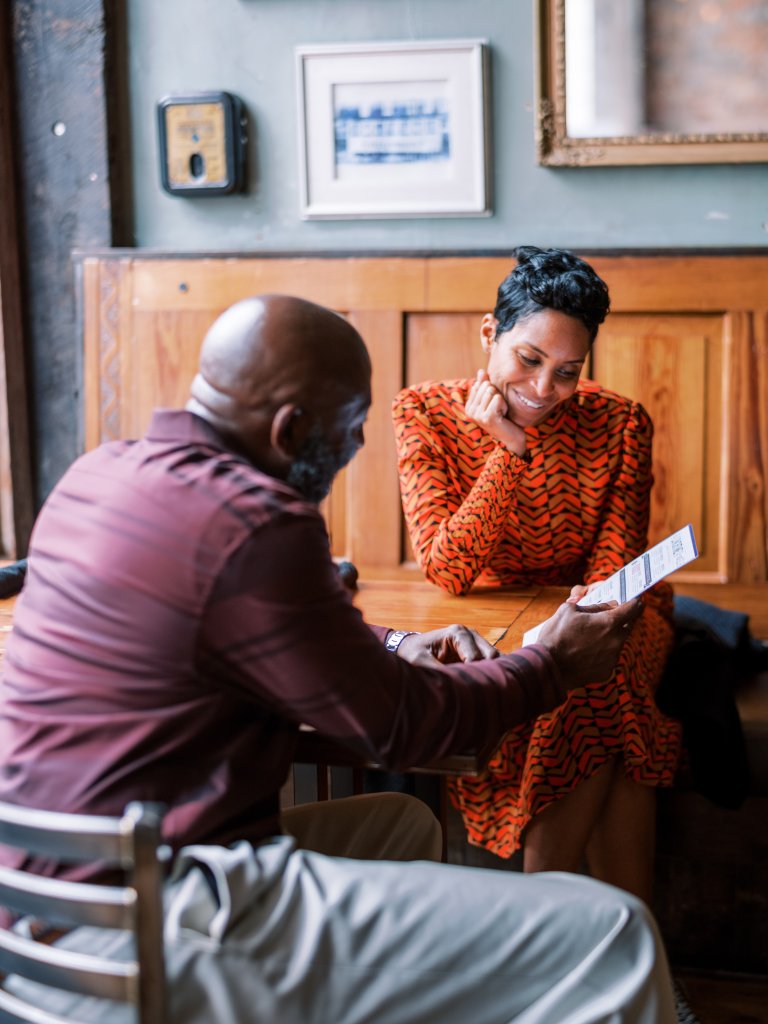 Two individuals are engaged in a conversation at a wooden table in a cozy setting, with one person showing a document to the other in Williamson County, Tennessee.