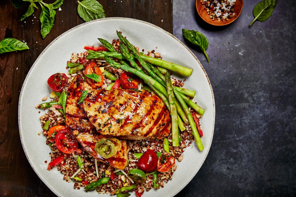 A plate of grilled chicken breast served over a colorful quinoa salad with asparagus, cherry tomatoes, and fresh herbs in Williamson County, Tennessee.