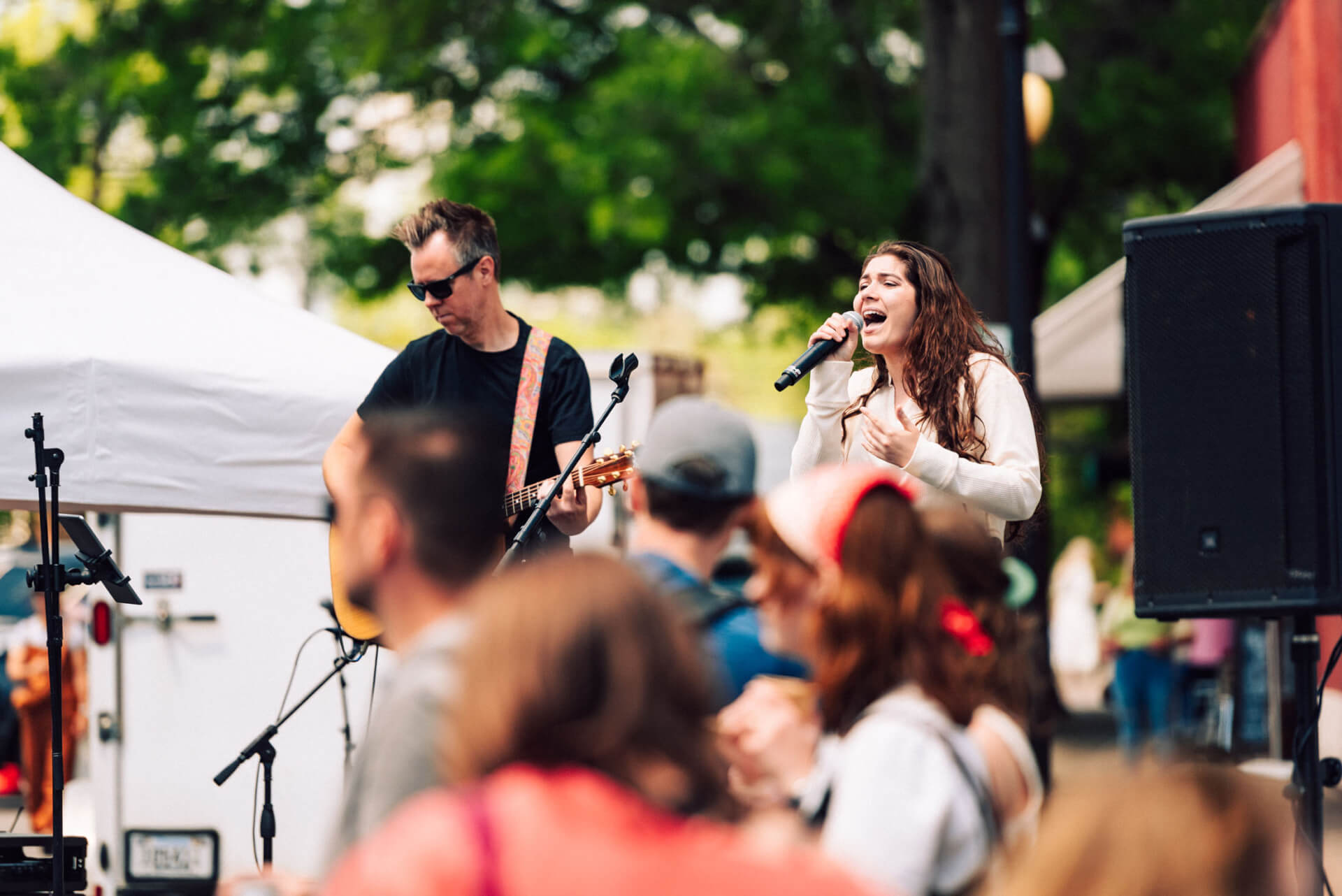 A lively outdoor concert with a band performing under a white tent, surrounded by an enthusiastic crowd enjoying the music in Williamson County, Tennessee.