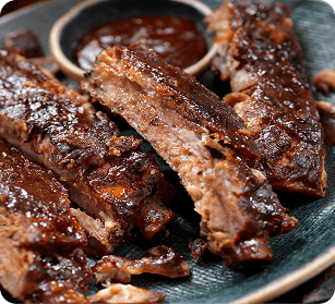 A plate of succulent, saucy baby back ribs with a side of barbecue sauce in Williamson County, Tennessee.