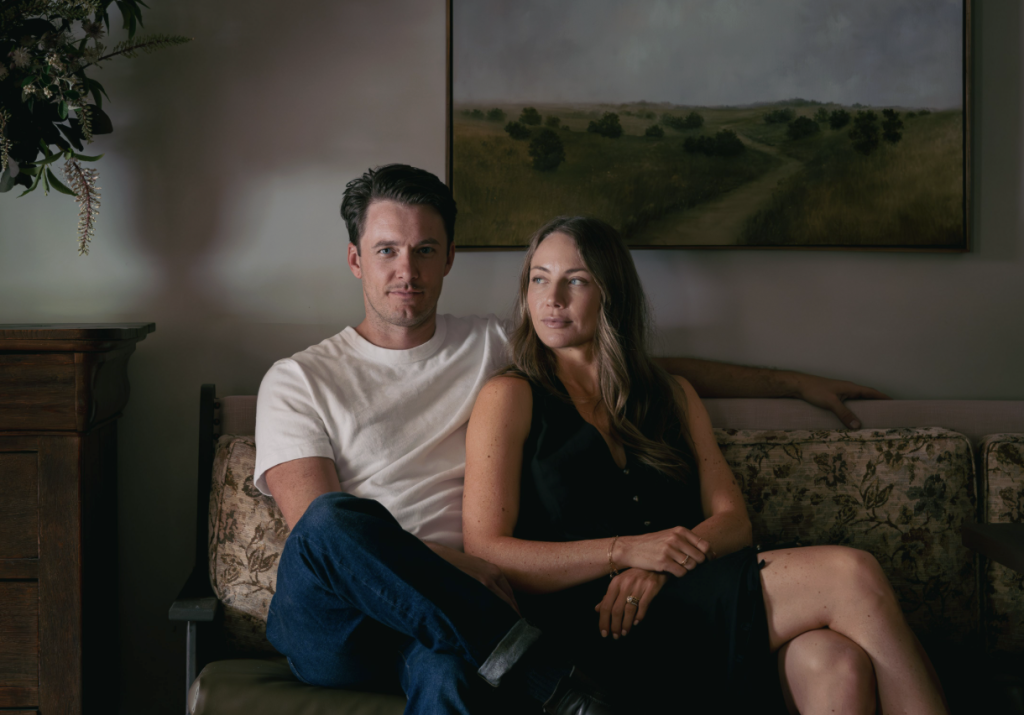 A couple sits comfortably on a floral-patterned couch, with a serene landscape painting hanging above them in Williamson County, Tennessee.