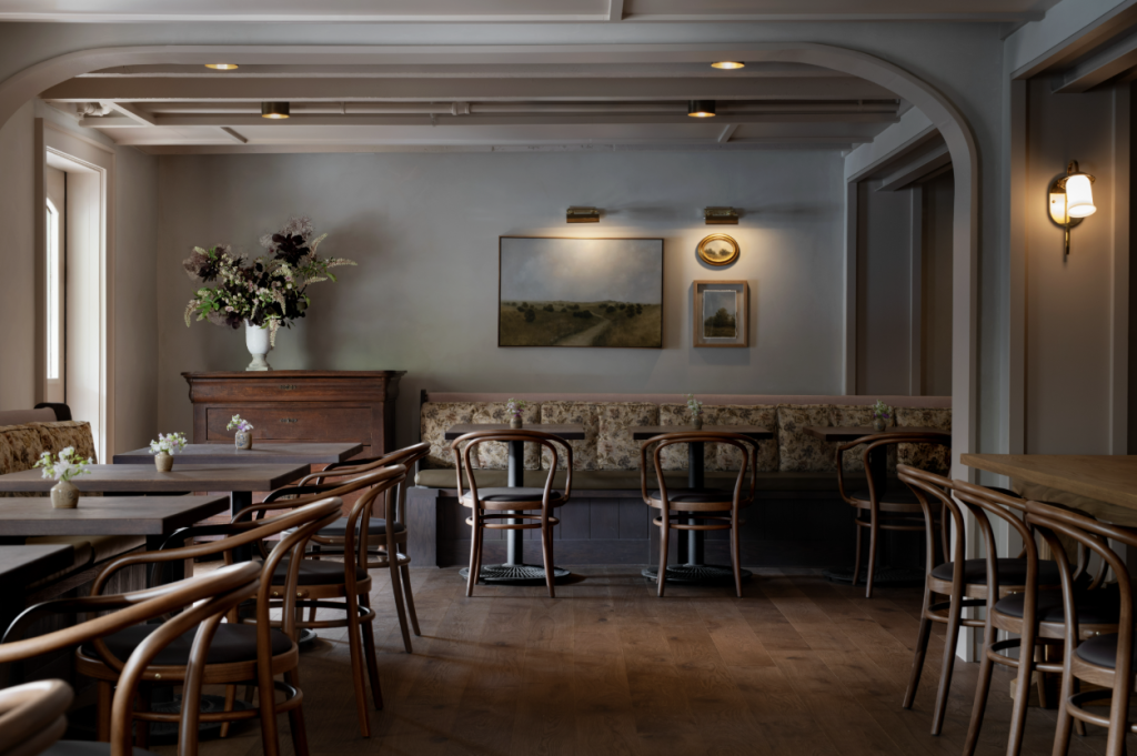 A cozy, rustic-style dining room with wooden furniture, floral-patterned cushions, and a large painting above a bench in Williamson County, Tennessee.