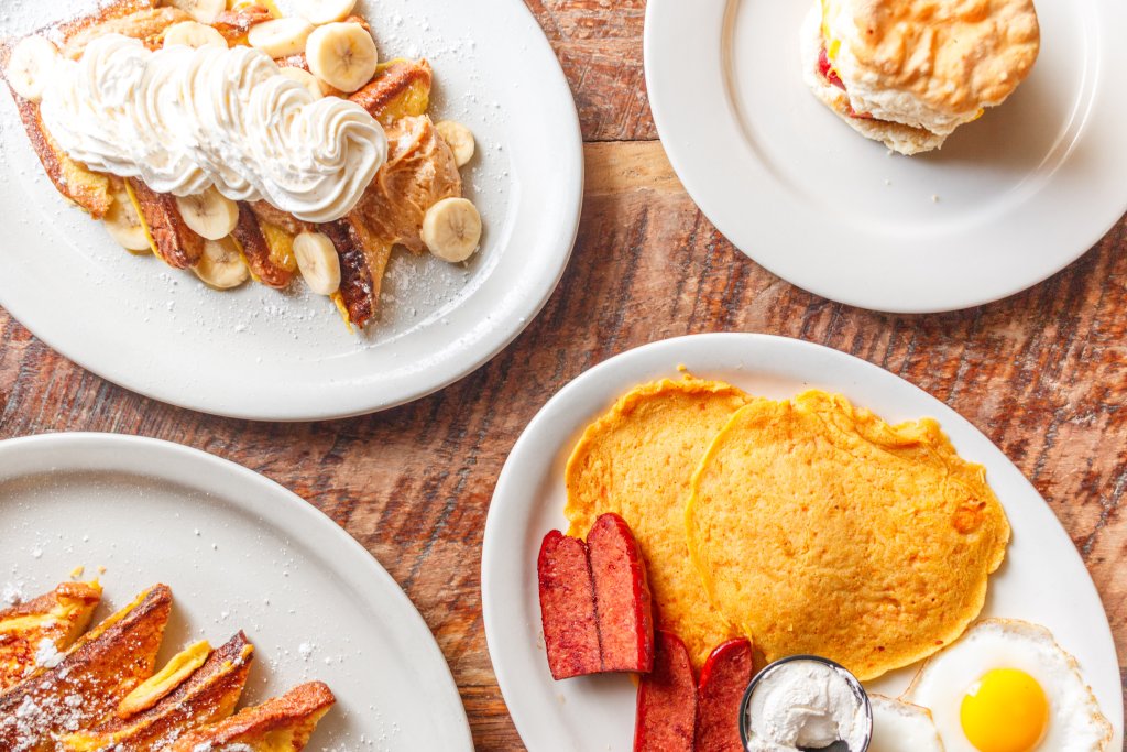A variety of breakfast dishes including French toast with whipped cream and bananas, pancakes with sausage and eggs, and a biscuit sandwich in Williamson County, Tennessee.