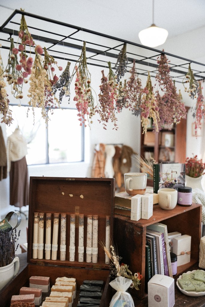 A charming shop interior with hanging dried flowers, wooden crates filled with books and bath products, and a cozy atmosphere in Williamson County, Tennessee.