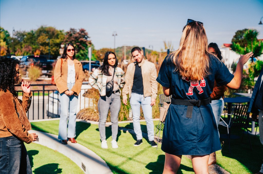 A group of people are gathered on a grassy area, with one person in the foreground gesturing towards the others in Williamson County, Tennessee.