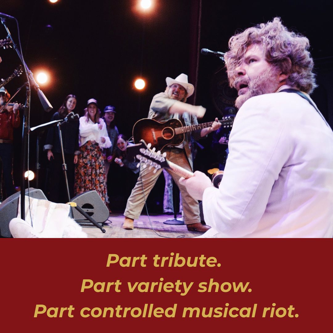 A lively musical performance featuring a diverse group of musicians on stage, including guitarists, a violinist, and a singer in a white suit, all under warm stage lighting in Williamson County, Tennessee.