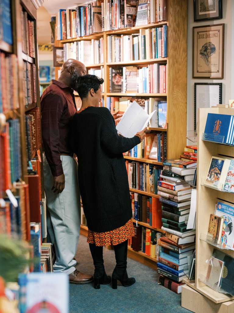 Plan the Perfect Reading Retreat in Franklin, TN with These Cozy Bookstores & Scenic Nooks A couple is browsing books in a cozy bookstore, surrounded by towering shelves filled with colorful volumes in Williamson County, Tennessee.
