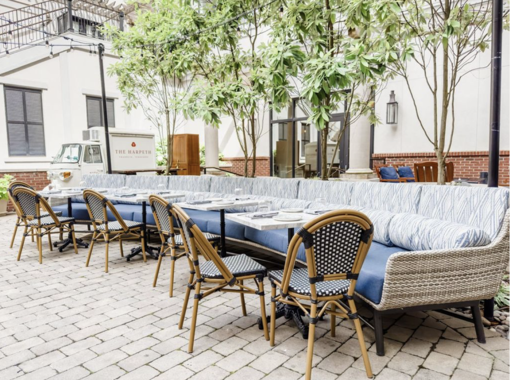 Outdoor seating area with blue and white striped cushions, wicker chairs, and potted plants in Williamson County, Tennessee.