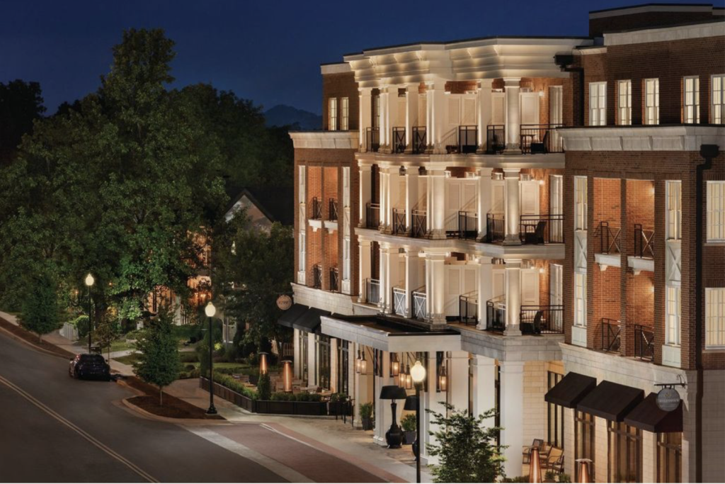 A beautifully lit, multi-story brick building with balconies and columns stands on a tree-lined street at night in Williamson County, Tennessee.
